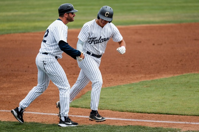 Assistant Coach Chris Vopinek (left) shakes hands with Isaiah Rios after a home run